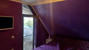 - une chambre avec un mur violet, un lit et une fenêtre dans l'établissement Апартамент-Надин, à Krumovgrad