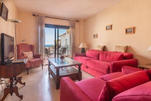 a living room with red couches and a television at 2233-Lovely 2 bedrooms on the beach, pool and port in Manilva
