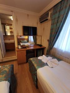 イスタンブールにあるアゴラ ブティック ホテル ＆ ビストロのベッド2台とデスクが備わるホテルルームです。