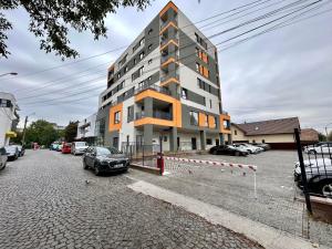 a tall building with cars parked in a parking lot at Happy Home in Târgu-Mureş