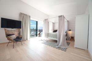 een witte slaapkamer met een bed, een stoel en een raam bij Slottsholmen Hotell och Restaurang in Västervik