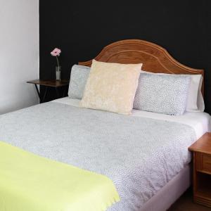 1 dormitorio con cama blanca y cabecero de madera en Hostal Victoria, en Altura 21 fotos más