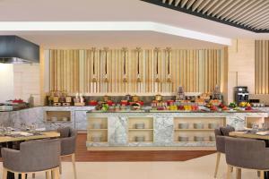 a restaurant with a counter with tables and chairs at Fairfield by Marriott Bali Kuta Sunset Road in Kuta