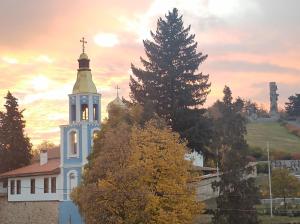 a church with a tower with a cross on it at Cozy Rooms Panagyurishte in Panagyurishte