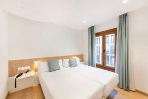 duże białe łóżko w pokoju z oknem w obiekcie Odyssey Rooms Alicante w Alicante