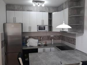 een keuken met witte kasten en een roestvrijstalen koelkast bij Apartman See in Bijeljina
