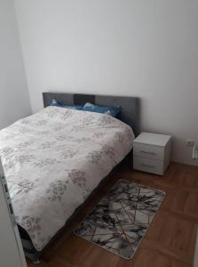 een slaapkamer met een bed met een witte sprei en een nachtkastje bij Apartman See in Bijeljina
