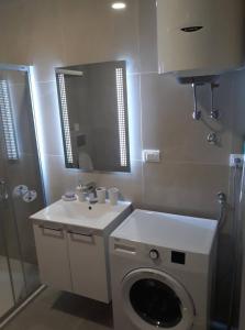 een badkamer met een wastafel en een wasmachine bij Apartman See in Bijeljina