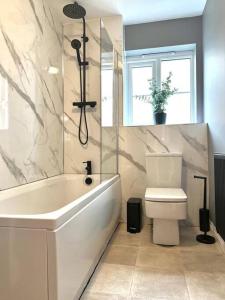 ein Badezimmer mit einer weißen Badewanne und einem WC in der Unterkunft Damson Drive- Boutique Home in Oldbury