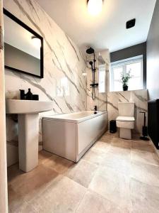 a bathroom with a sink and a tub and a toilet at Damson Drive- Boutique Home in Oldbury