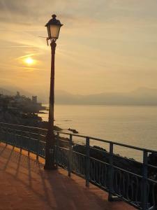 ein Straßenlicht neben einem Zaun und dem Meer in der Unterkunft Dai Pescatori Nervi in Genua