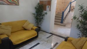 a living room with a yellow couch and a staircase at Cresta Beach Studios in St. Julianʼs