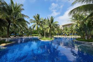 a large swimming pool with palm trees in a resort at Four Points by Sheraton Shenzhou Peninsula Resort in Wanning