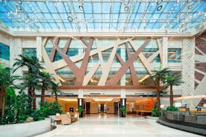 a lobby of a building with palm trees and a ceiling at Four Points by Sheraton Qingdao, Chengyang in Qingdao