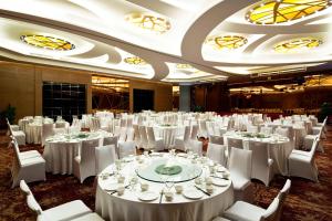um grande salão de banquetes com mesas e cadeiras brancas em Four Points by Sheraton Qingdao, Chengyang em Qingdao