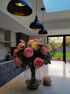 Little Missenden的住宿－Homely 5 bed Cottage 30 mins to Heathrow, London, Legoland, Windsor Castle，一张桌子上满是粉红色和黄色玫瑰的花瓶