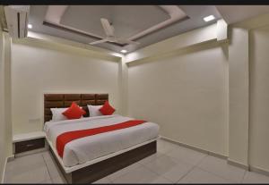 a bedroom with a bed with red pillows and a ceiling at HOTEL SUNWAY in Ahmedabad