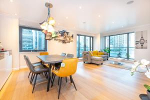 uma sala de jantar e sala de estar com mesa e cadeiras em Luxurious Modern 3BR Flat in Prime Canary Wharf em Londres