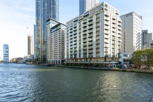 a river in a city with tall buildings at Luxurious Modern 3BR Flat in Prime Canary Wharf in London