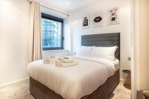 a bedroom with a bed with towels on it at Luxurious Modern 3BR Flat in Prime Canary Wharf in London