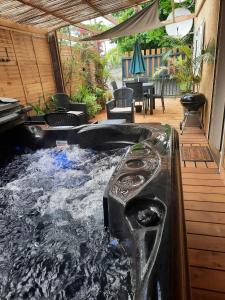 a hot tub in a patio with a table and chairs at La Caz Anaïs avec jacuzzi in Saint-Joseph