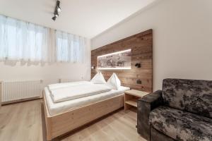 a bedroom with a bed and a chair at Dolomite Apartments Winklwiese 6&7 in San Candido