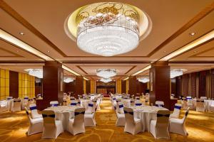 a banquet hall with white tables and chairs and a chandelier at Four Points by Sheraton Danzhou in Danzhou