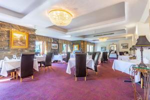 un comedor con mesas y sillas blancas en Whitewater Hotel & Spa, en Newby Bridge