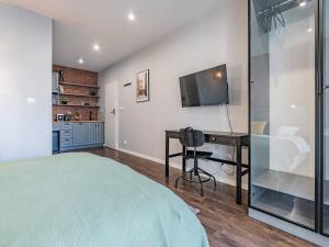 a bedroom with a bed and a desk and a tv at Hello Apartments Modern Industrial Browar Gdański in Gdańsk