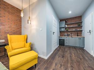 a yellow chair in a room with a kitchen at Hello Apartments Modern Industrial Browar Gdański in Gdańsk