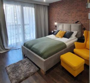 a bedroom with a large bed and a yellow chair at Hello Apartments Modern Industrial Browar Gdański in Gdańsk