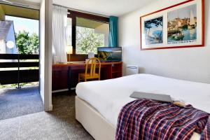 a bedroom with a bed and a desk with a computer at Kyriad Lannion-Perros-Guirec in Lannion +51 photos