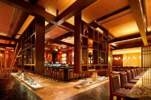 a restaurant with wooden ceilings and chairs and a bar at Sheraton Jiangyin Hotel in Jiangyin