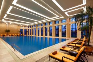 a large swimming pool in a hotel lobby with chairs at Sheraton Jiangyin Hotel in Jiangyin