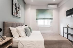 1 dormitorio con 1 cama grande con sábanas y almohadas blancas en "Sunbow Jungle" - New Boutique Apt Downtown Athens en Athens