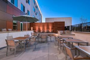 an outdoor patio with tables and chairs and an umbrella at Element Palmdale in Palmdale
