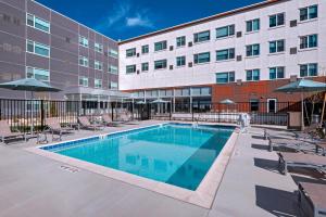 a pool in front of a building with chairs and umbrellas at Element Palmdale in Palmdale