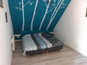 een slaapkamer met een bed met bomen aan de muur bij Gîte de la chênaie in Avrillé-les-Ponceaux
