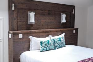 1 dormitorio con cabecero de madera y cama con almohadas en Résidence Le Beau Rivage, en Bandol