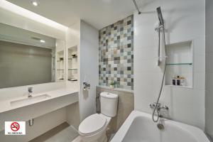 a white bathroom with a toilet and a sink at Prom Hotel in Bangkok