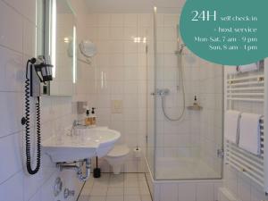 uma casa de banho com um lavatório, um chuveiro e um WC. em Classik Hotel Martinshof München Messe em Munique