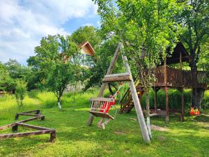 a playground with a swing and a tree house at La sat - Mândră Ioană in Bertea