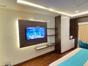 Habitación de hotel con TV de pantalla plana en la pared en Hilarity Inn, en Padappai