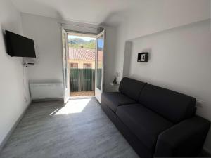 sala de estar con sofá negro y ventana en Studio Amélie-les-Bains-Palalda, 1 pièce, 2 personnes - FR-1-659-91, en Amélie-les-Bains-Palalda