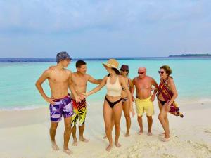 een groep mensen die op een strand staan bij VIVA Beach Maldives in Hangnaameedhoo