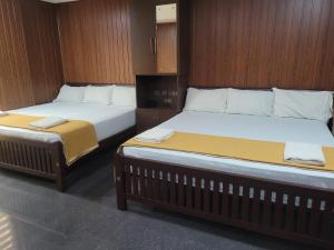 two beds in a room with wooden walls at Ashoka Inn Chottanikkara in Chottanikara