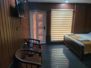 a room with a bed and two chairs and a window at Ashoka Inn Chottanikkara in Chottanikara