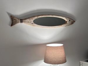 a wooden fish shaped mirror on a ceiling with a lamp at Bel Air surf escape in El Cotillo