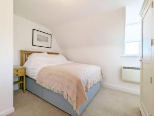 ein kleines weißes Schlafzimmer mit einem Bett und einem Fenster in der Unterkunft Badgers Cottage 