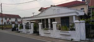 ein weißes Haus mit einem Zaun an einer Straße in der Unterkunft Penginapan Terdekat (Near) in Bukittinggi